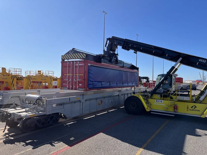 A containerised vehicle transport unit is loaded onto a wagon at the Port of Darwin for rail transport to southern markets